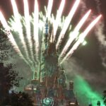 香港ディズニーランドの城に打ち上がる夜の花火。緑と白の光線が城全体を明るく照らしている