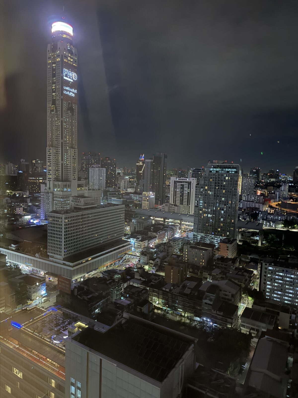 バークレーホテルの客室から見たバンコクの夜景。中央に高くそびえるバイヨークタワーの照明が光る