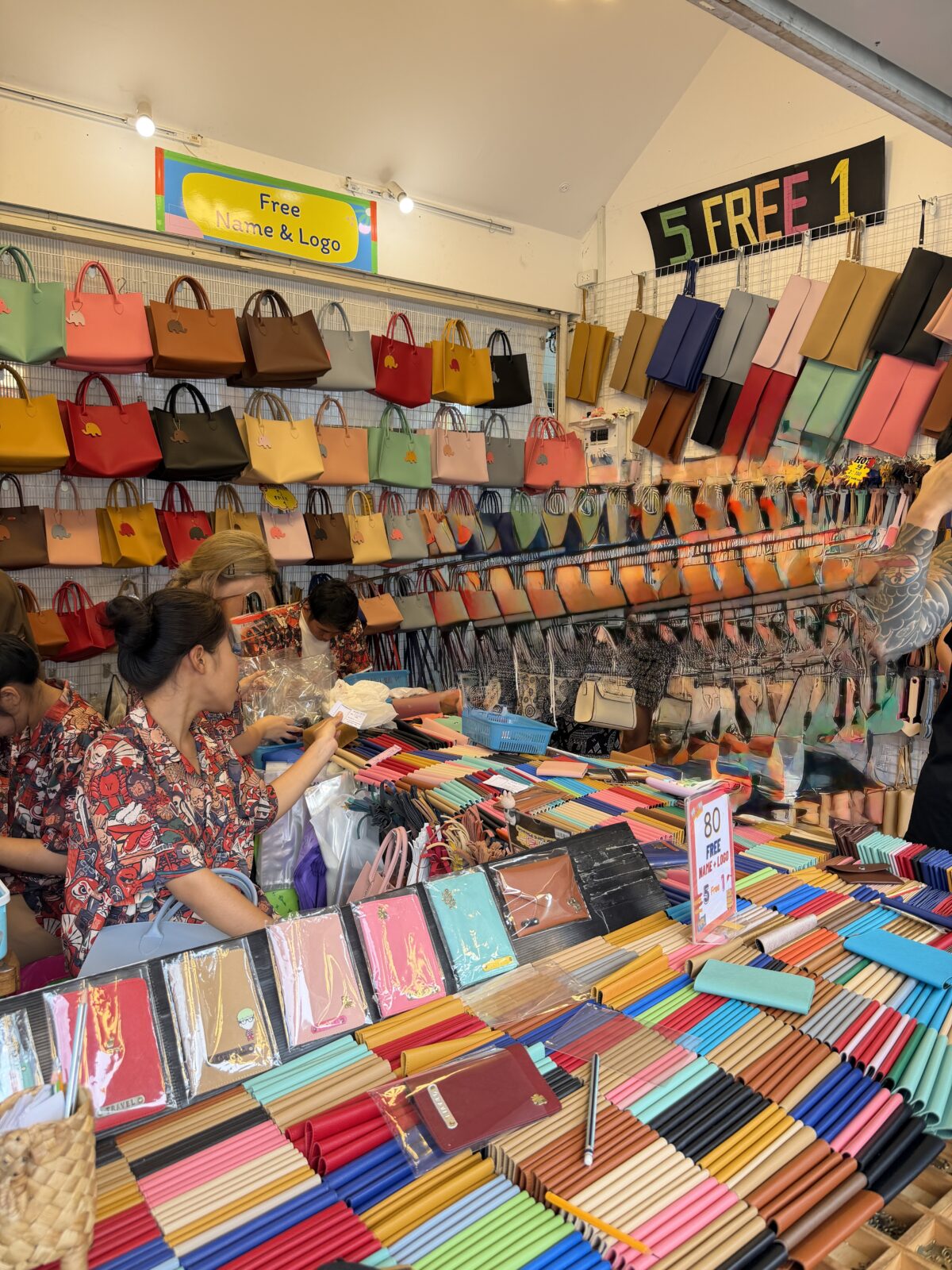 チャトゥチャック市場の革製品店。棚にバッグが並び、5 FREE 1と書かれた黄色い札が下がっている