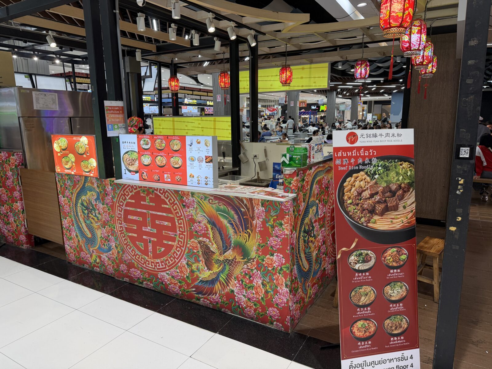 Big Cのフードコートの牛肉麺の店。赤い装飾のカウンターにメニューの写真が並ぶ