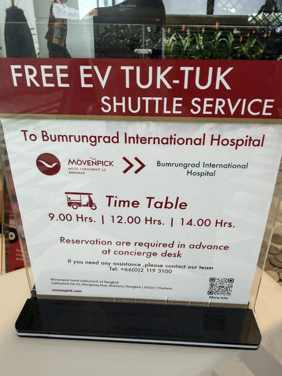 モーベンピックのロビーに置かれた無料EVトゥクトゥクの案内。バムルンラード国際病院行きで9時・12時・14時発、要事前予約と書かれている