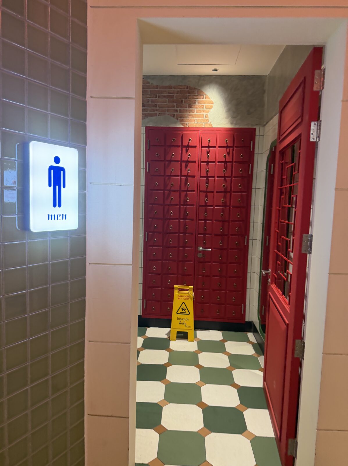Terminal21のPier21のトイレ入口。MENの表示があり、緑と白の市松模様の床と赤い扉が見える