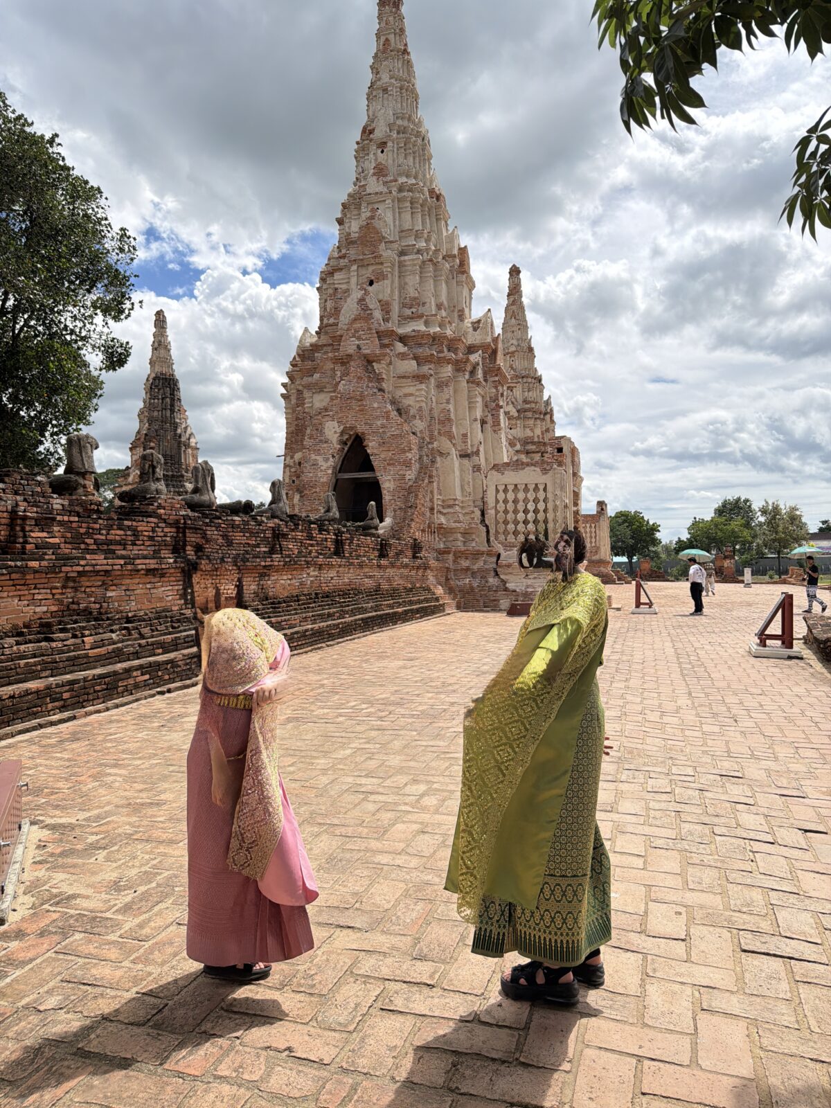 ワット・チャイワッタナラームの塔と、タイ衣装をレンタルして歩く2人の後ろ姿