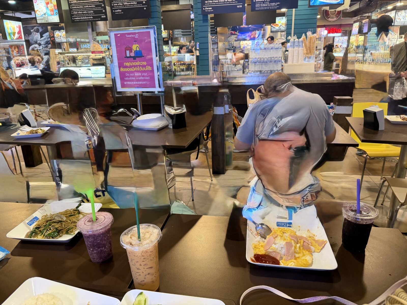 Pier21のテーブルに並んだ食事。炒め麺、オムレツの皿、紫色のスムージーとタイティーがトレーに載っている
