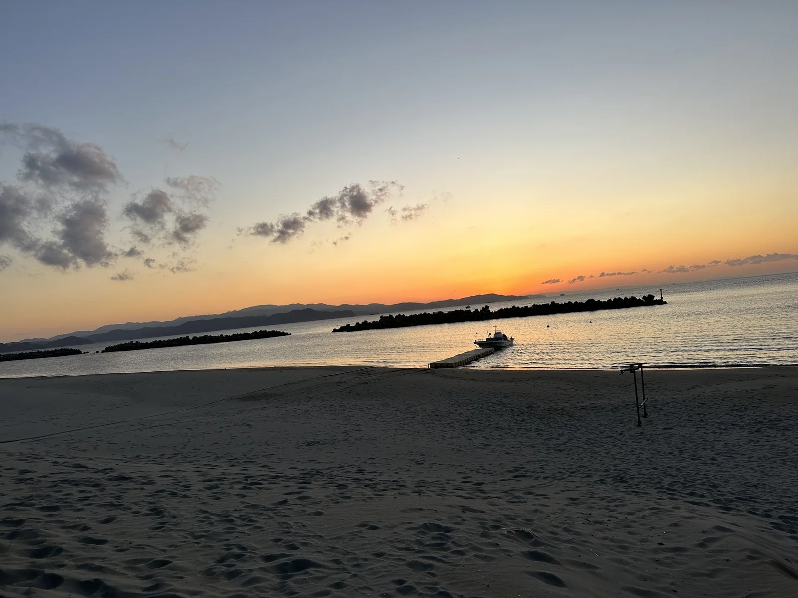 ホテル前の砂浜から見た夕日と防波堤