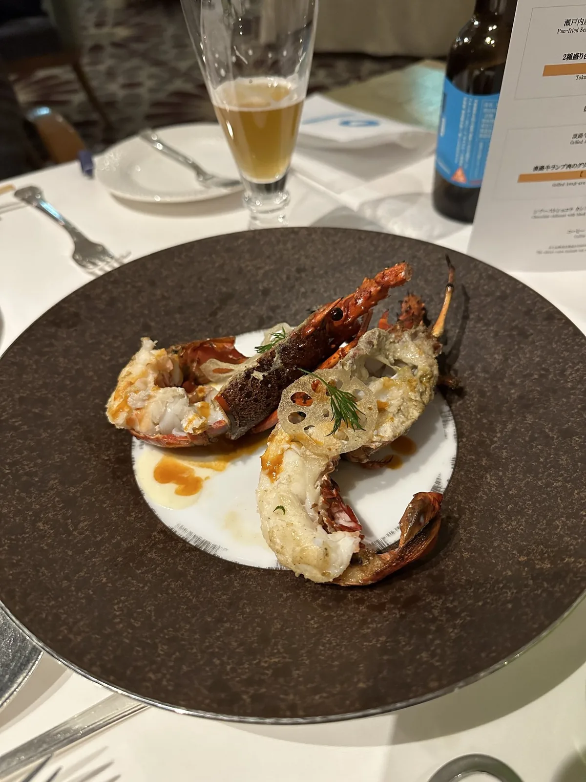 ホテルのレストラン「フォーシーズン」の夕食。黒い皿に盛られた伊勢海老の料理とビール