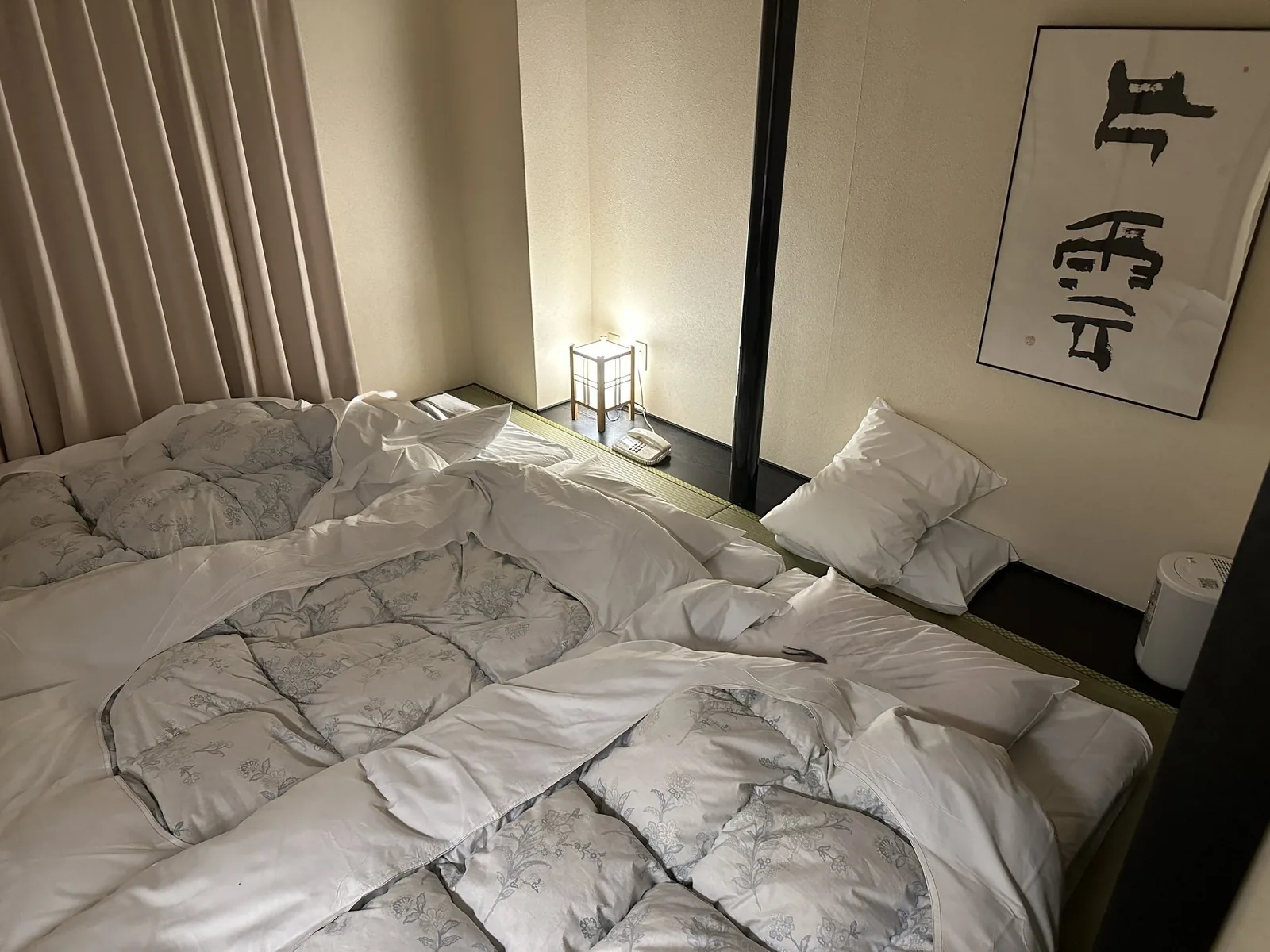 ジャパニーズデラックスの和室。畳の上に布団が並び、壁に掛け軸がかかっている