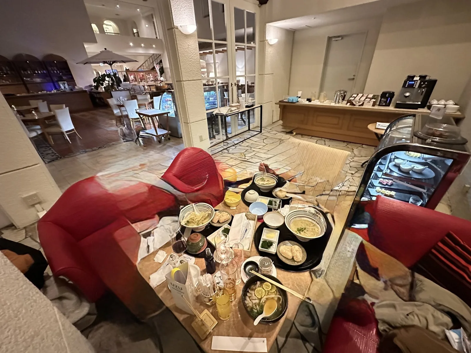 JTBラウンジの昼食。うどんとラーメンのどんぶりが並んだテーブルと赤い椅子