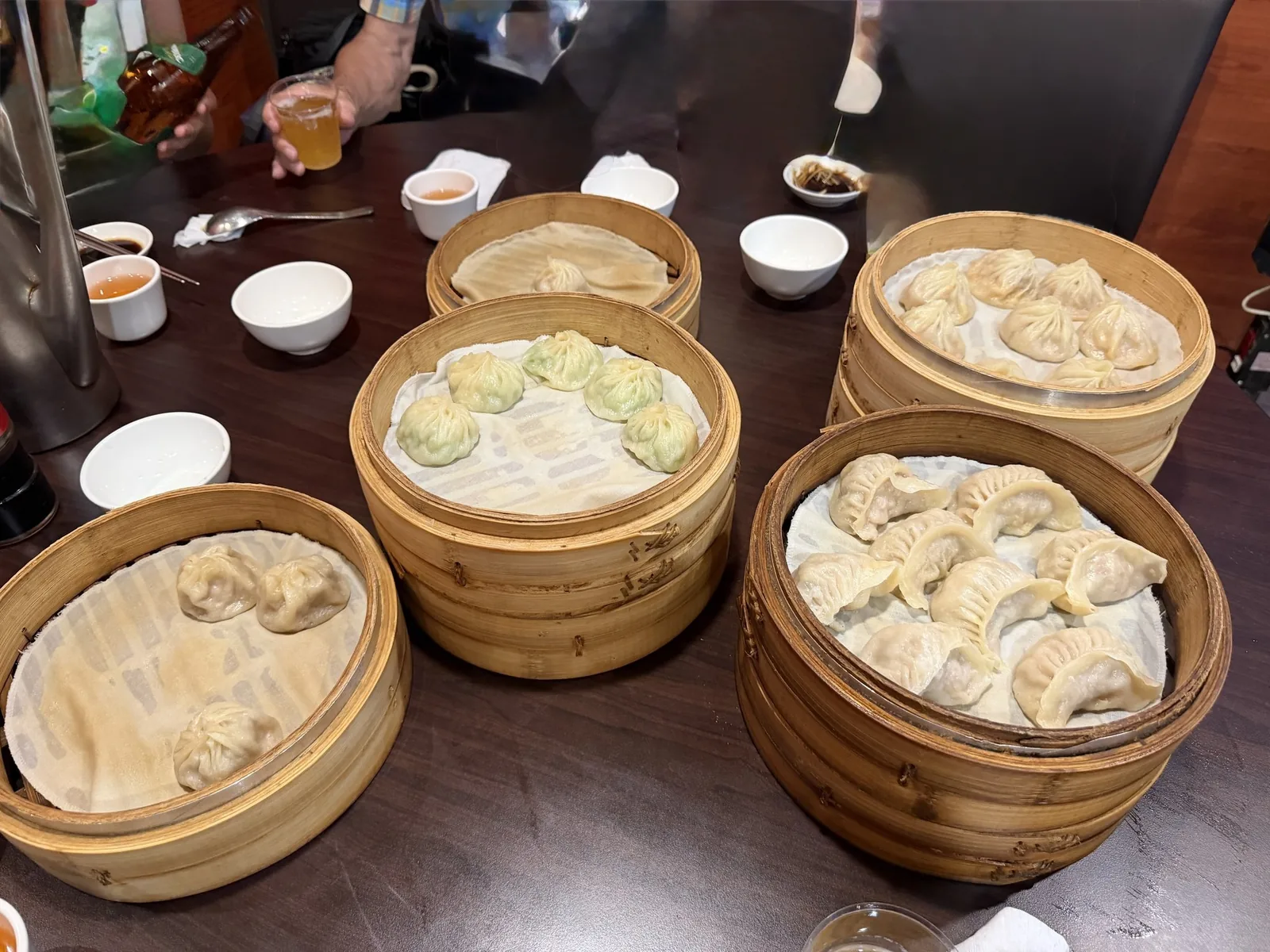 明月湯包のテーブルに並んだせいろ4つ。小籠包と焼き餃子、取り皿とビールが置かれている