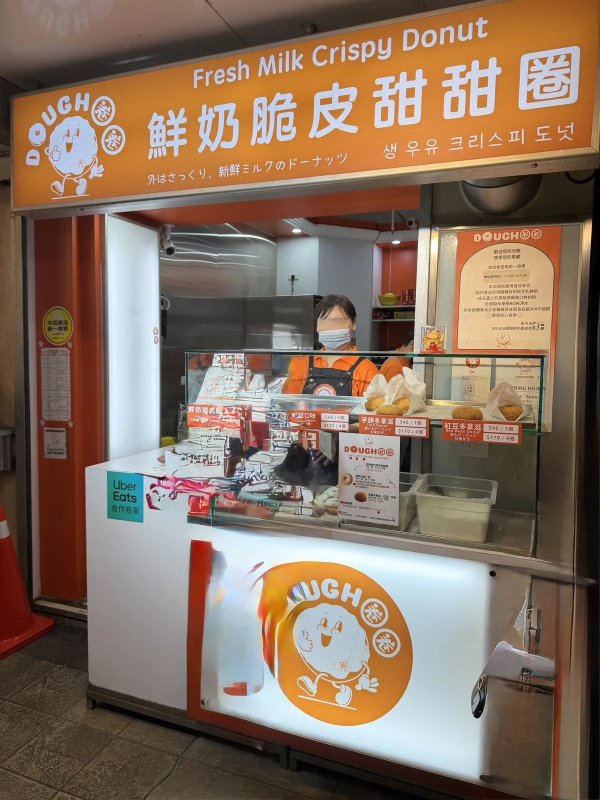 脆皮鮮奶甜甜圈(Dough)の店舗。ガラス越しに揚げたてのドーナツが並び、店員が接客している