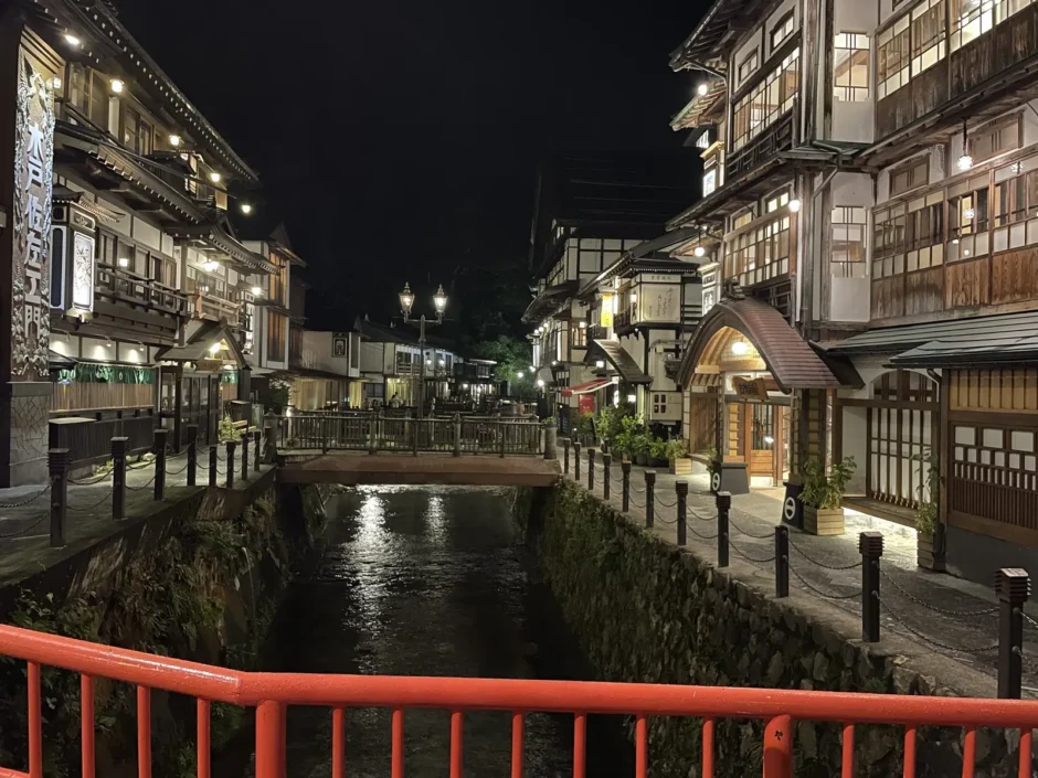 夜の銀山温泉。赤い欄干の橋から、明かりのともった旅館街と川を見たところ