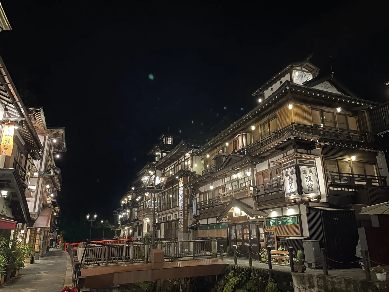 夜の銀山温泉。川沿いに明かりのともった木造の旅館が何軒も並んでいる