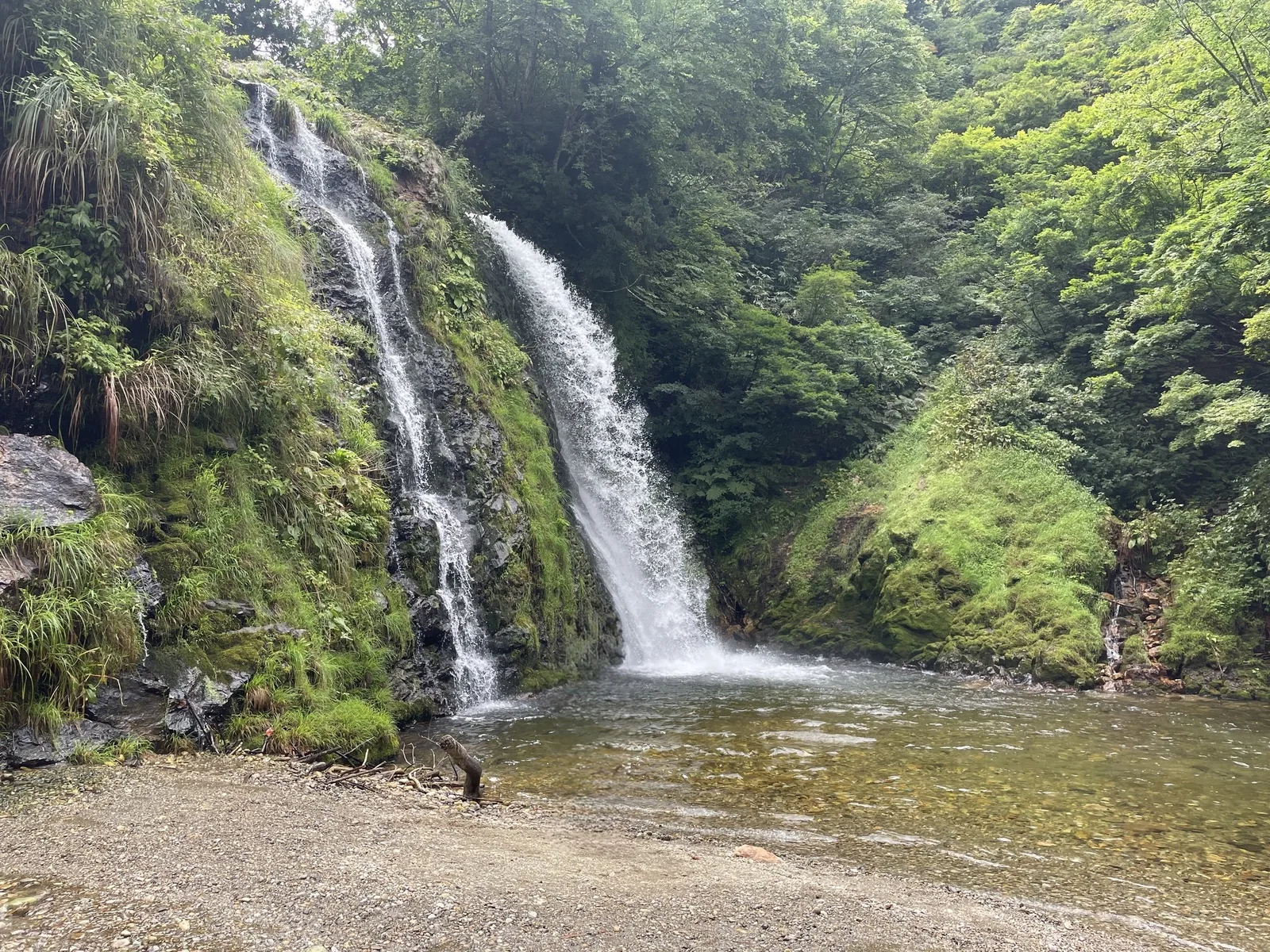 白銀の滝。緑の岩肌を2本の滝が流れ落ち、手前に浅い滝つぼが広がっている