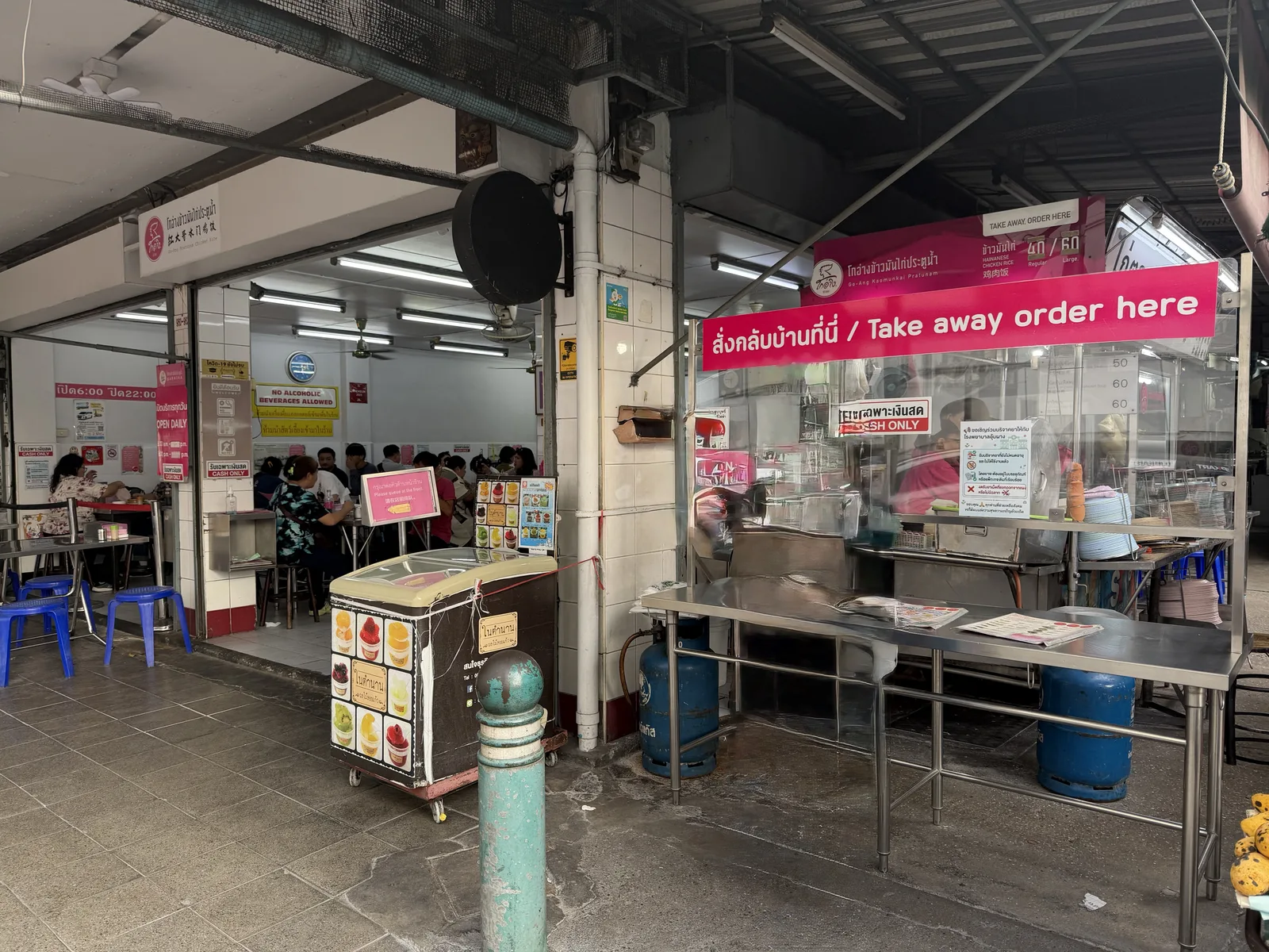ゴーアン・カオマンガイ・プラトゥーナムの店先。ピンクの看板に「Take away order here」と書かれ、持ち帰りカウンターにカオマンガイ40バーツ・60バーツの表示がある