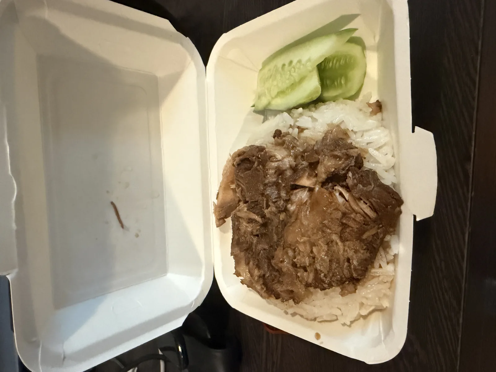 ゴーアンの持ち帰り容器を開けたところ。茶色く煮込んだ豚肉がご飯の上にのり、きゅうりが添えられている