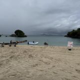 曇り空の伊計ビーチ。浜に引き上げられたボートと、沖に浮かぶ小島