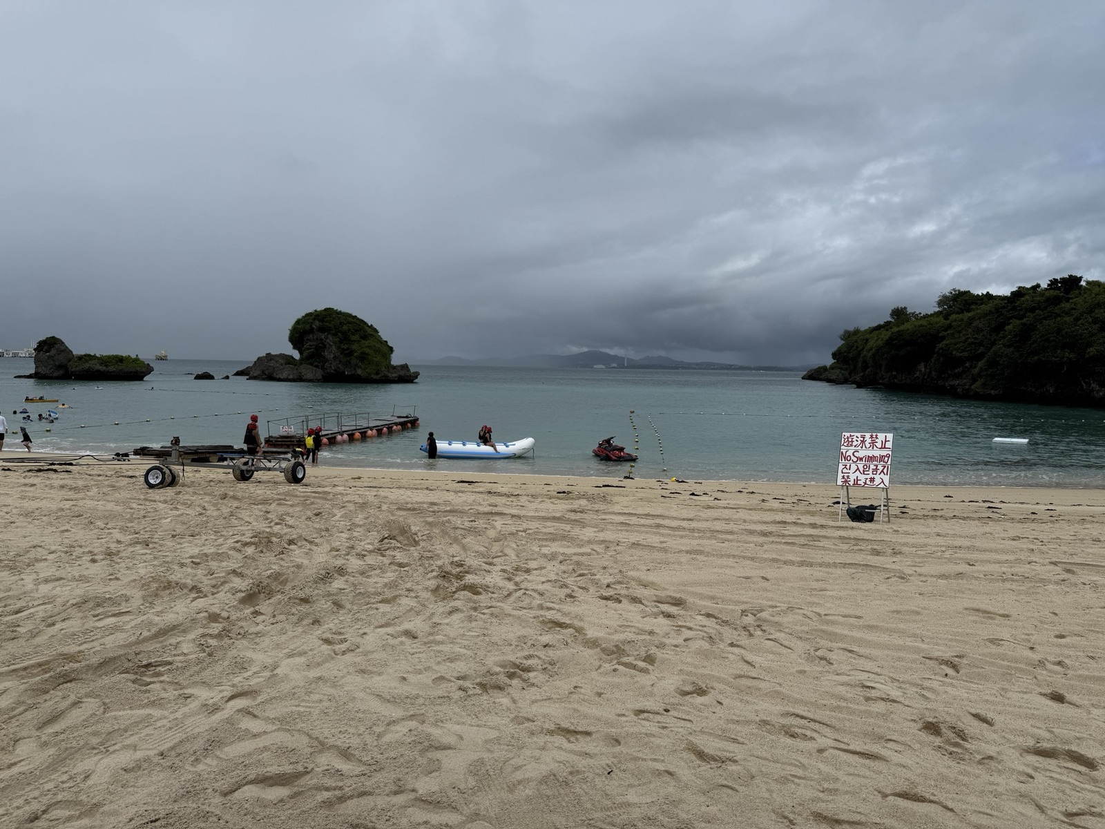 曇り空の伊計ビーチ。浜に引き上げられたボートと、沖に浮かぶ小島