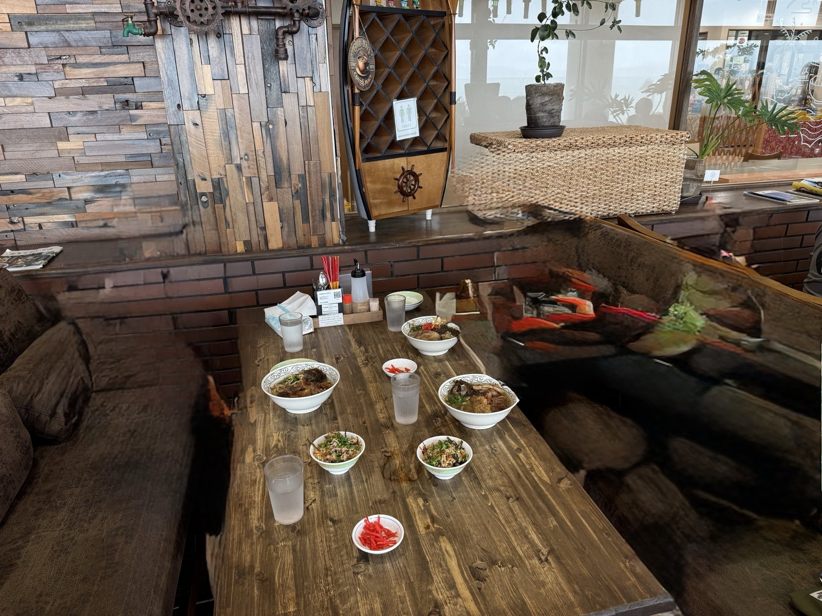海中茶屋の木のテーブルに、家族8人分の沖縄そばの丼と紅生姜が並んでいる