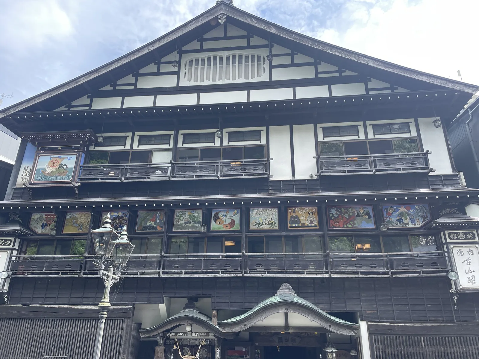 銀山温泉の古山閣の外観。格子の窓と絵の飾りが並ぶ木造の旅館