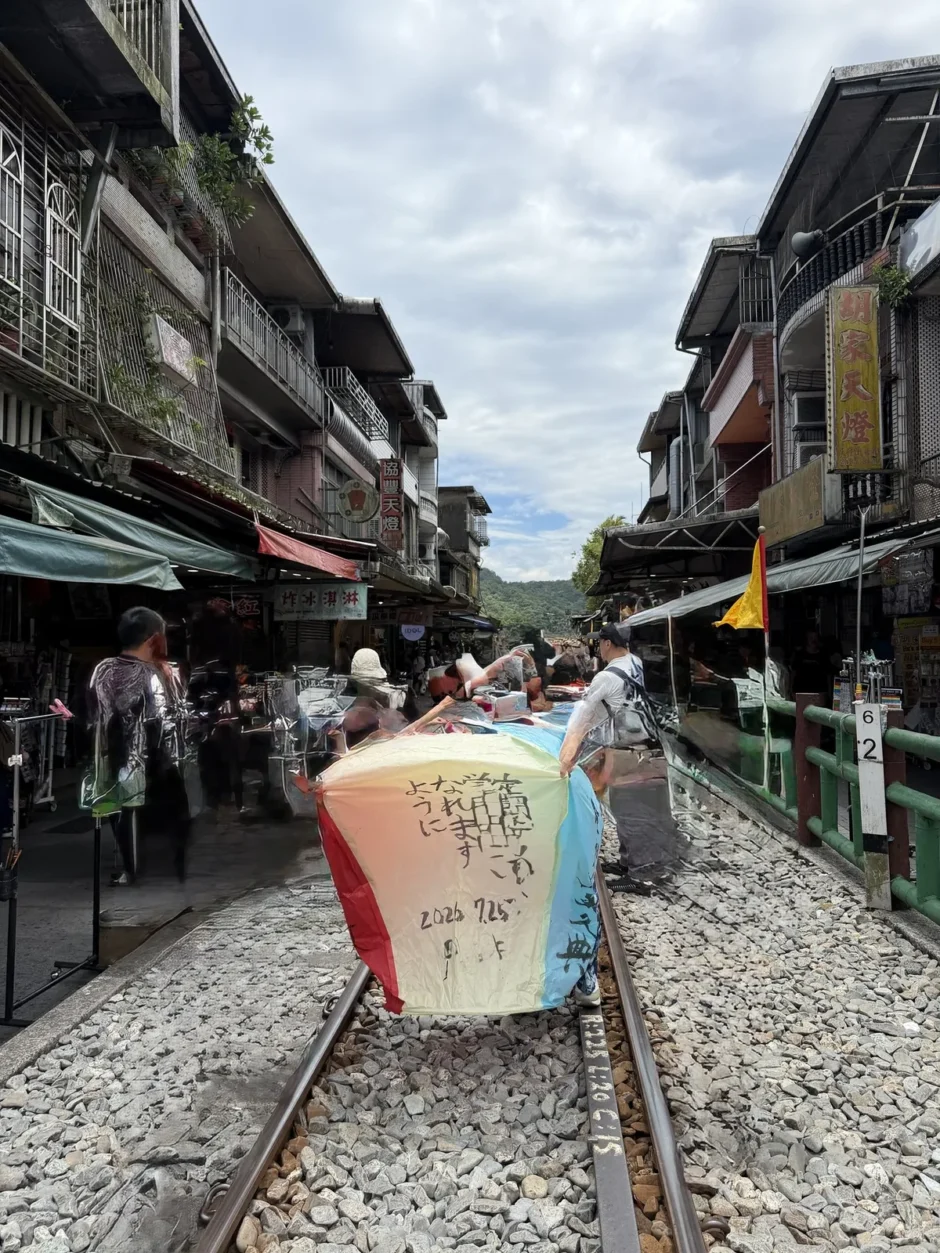 十分の線路の上に置かれた四色の天燈。日本語で書かれた願い事と日付が大きく写っている