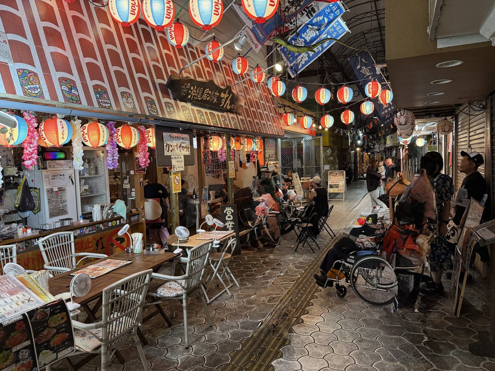 夜の沖縄居酒家すんの前。提灯が並び、店の前に車椅子が置かれている