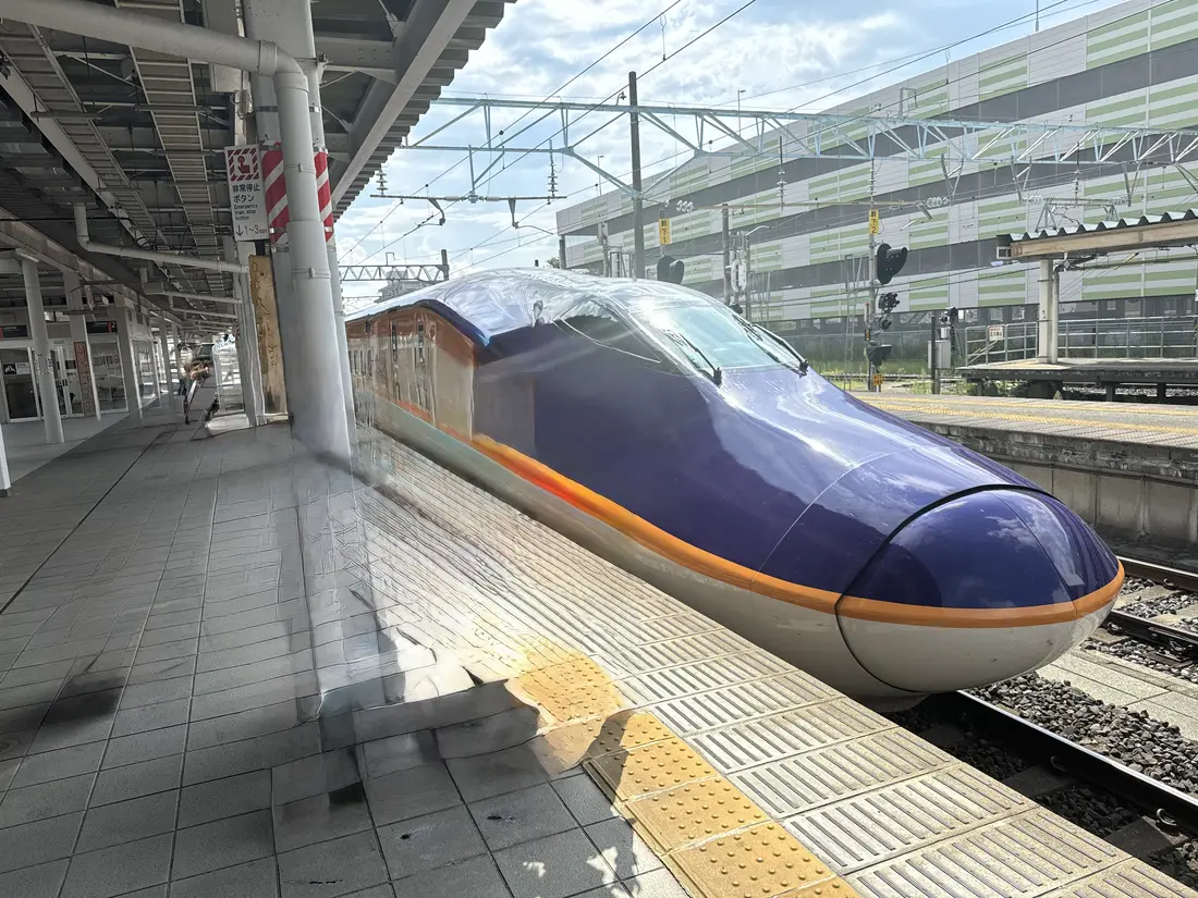 山形新幹線つばさが駅のホームに停まっている。紫と白の車体