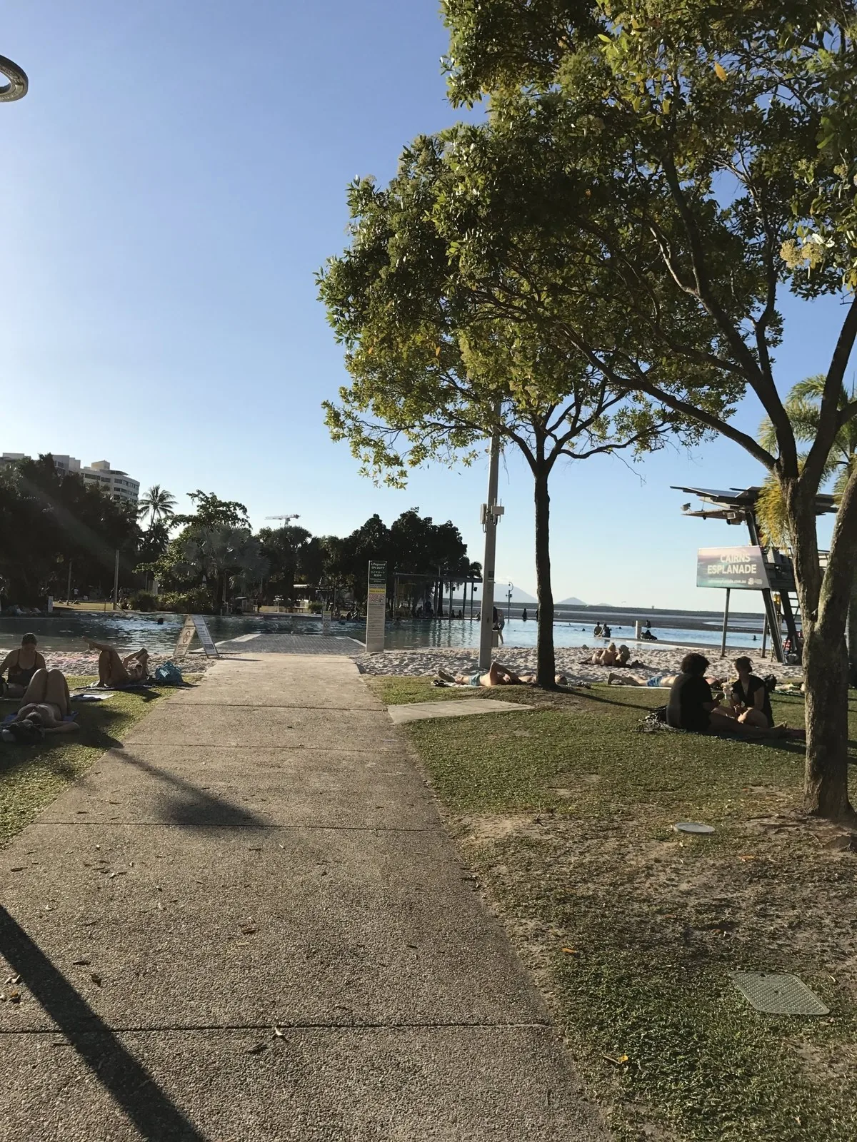 ケアンズ・エスプラネードの遊歩道と芝生、奥にラグーンプールとCAIRNS ESPLANADEの看板