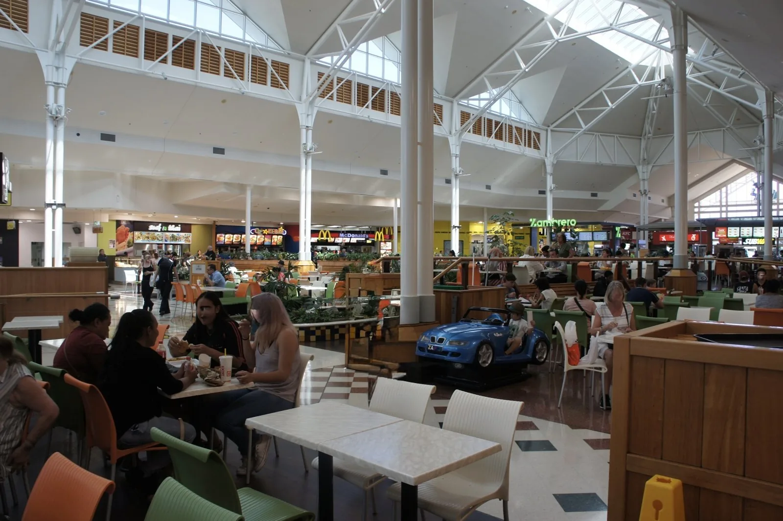 A food court in an atrium with skylights, with counters for McDonald's, KFC, and other restaurants at the back