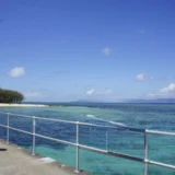 ケアンズ沖のグリーン島で、桟橋の手すり越しに見たエメラルド色の浅い海と白い砂浜（2017年9月）