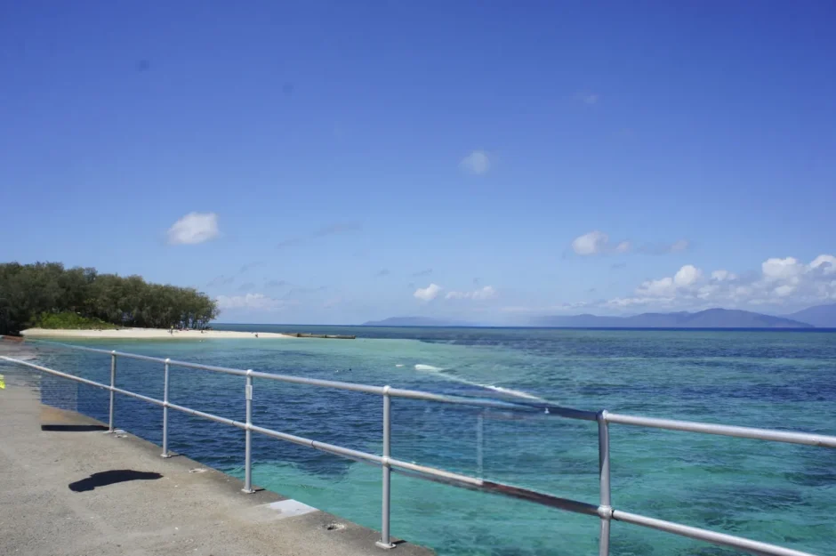 ケアンズ沖のグリーン島で、桟橋の手すり越しに見たエメラルド色の浅い海と白い砂浜（2017年9月）
