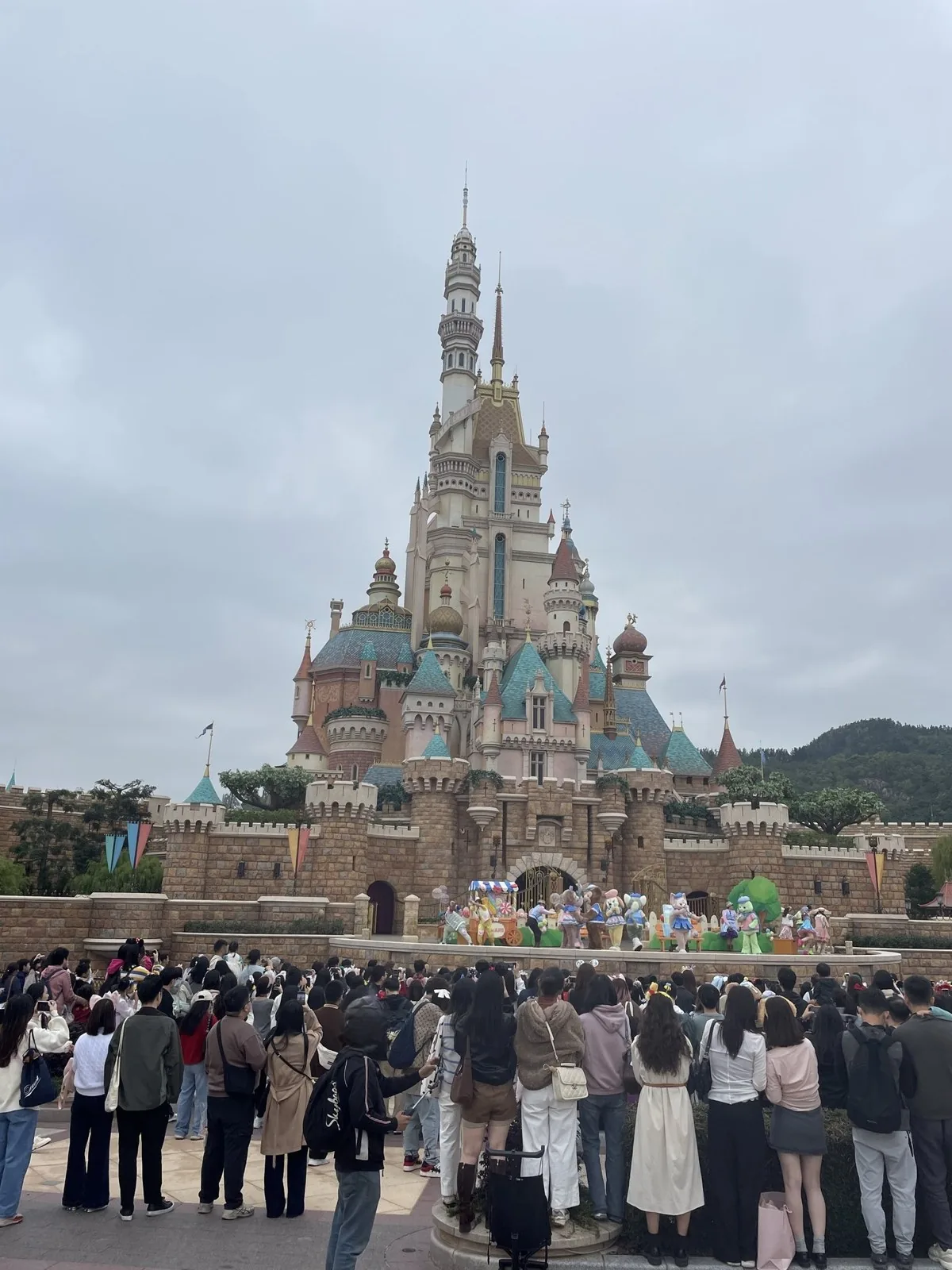 香港ディズニーランドのキャッスル・オブ・マジカルドリームの前に大勢の観客が集まり、城前のショーを見ている様子