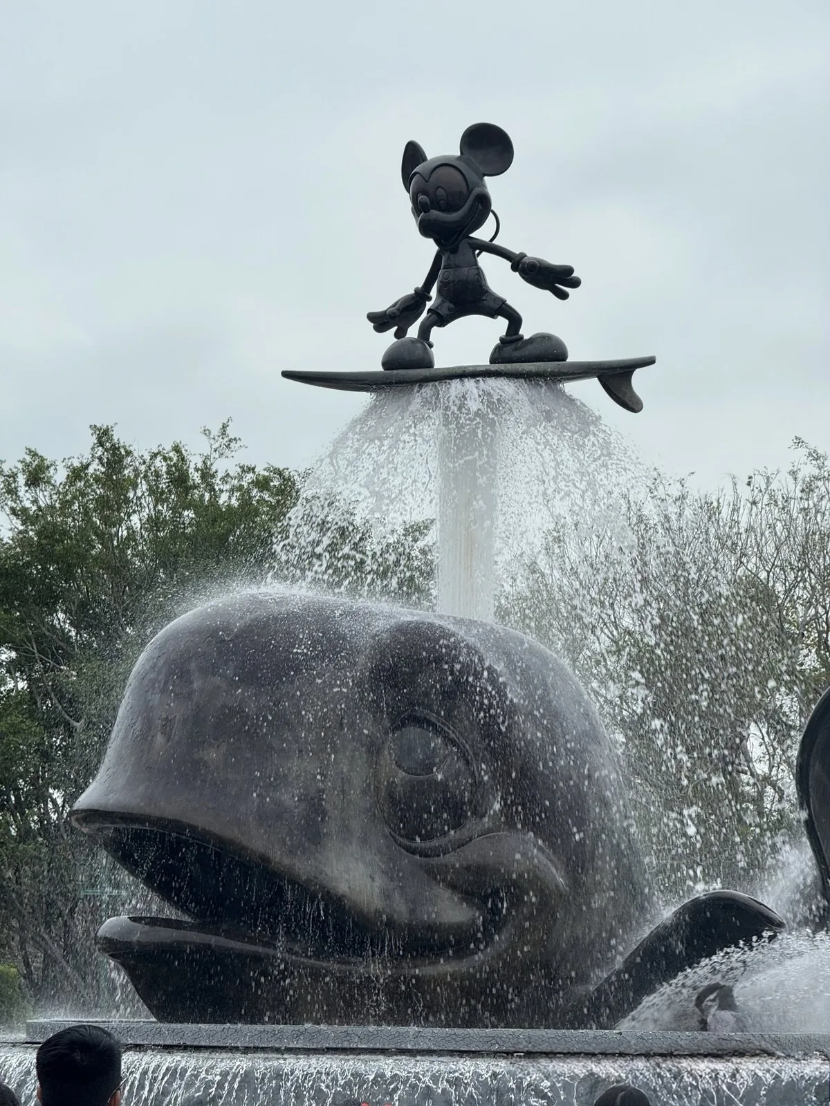 香港ディズニーランド入口の噴水。サーフボードに乗るミッキーマウス像とクジラ像から水が噴き上がっている