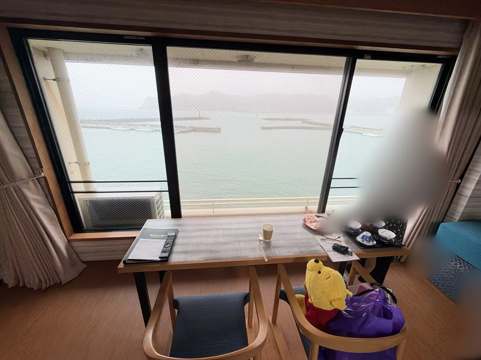 客室の窓辺の机と椅子。窓の外に小湊の海が見える