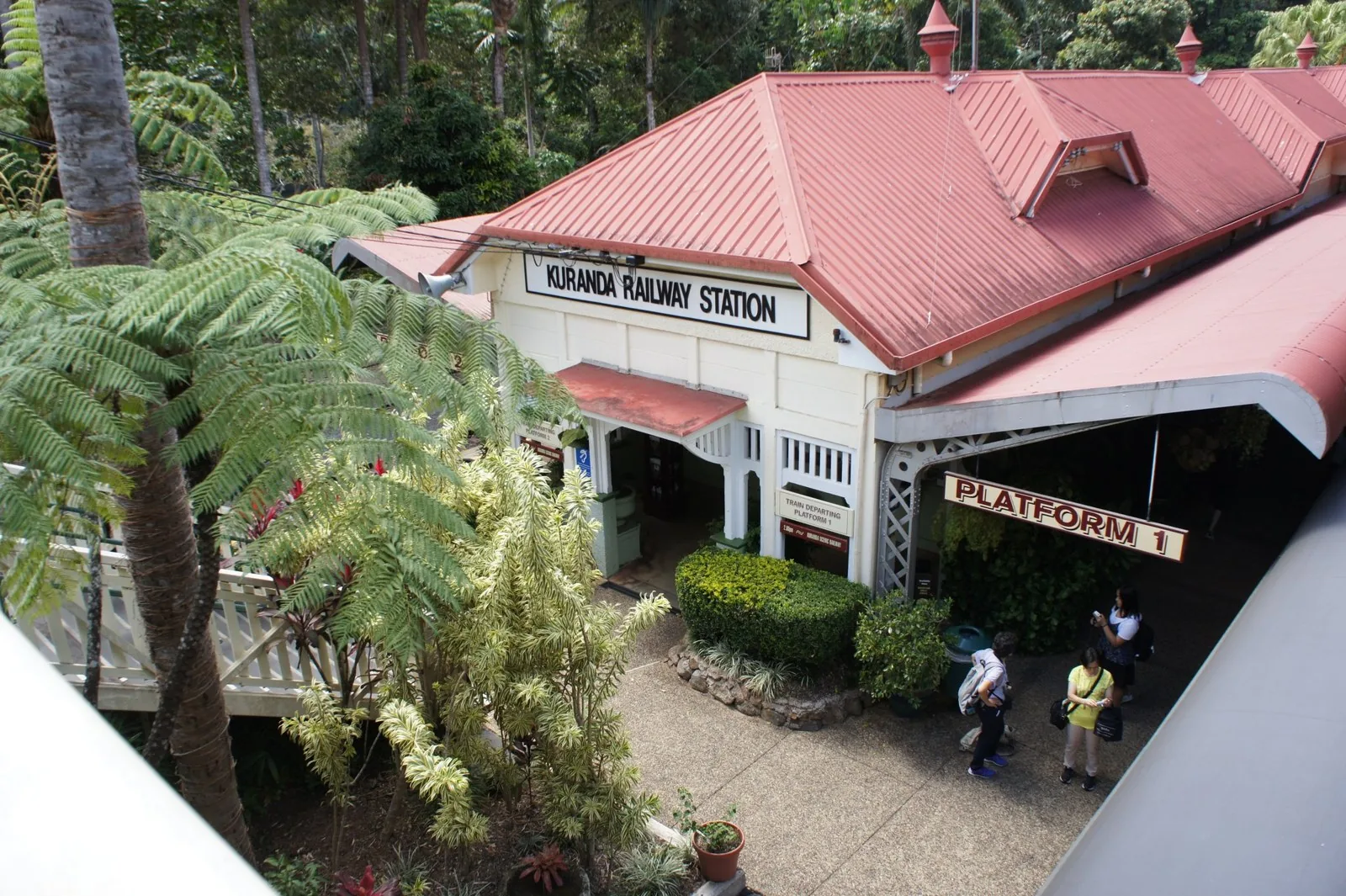 赤い屋根に「KURANDA RAILWAY STATION」の看板があるキュランダ駅舎と熱帯の木々