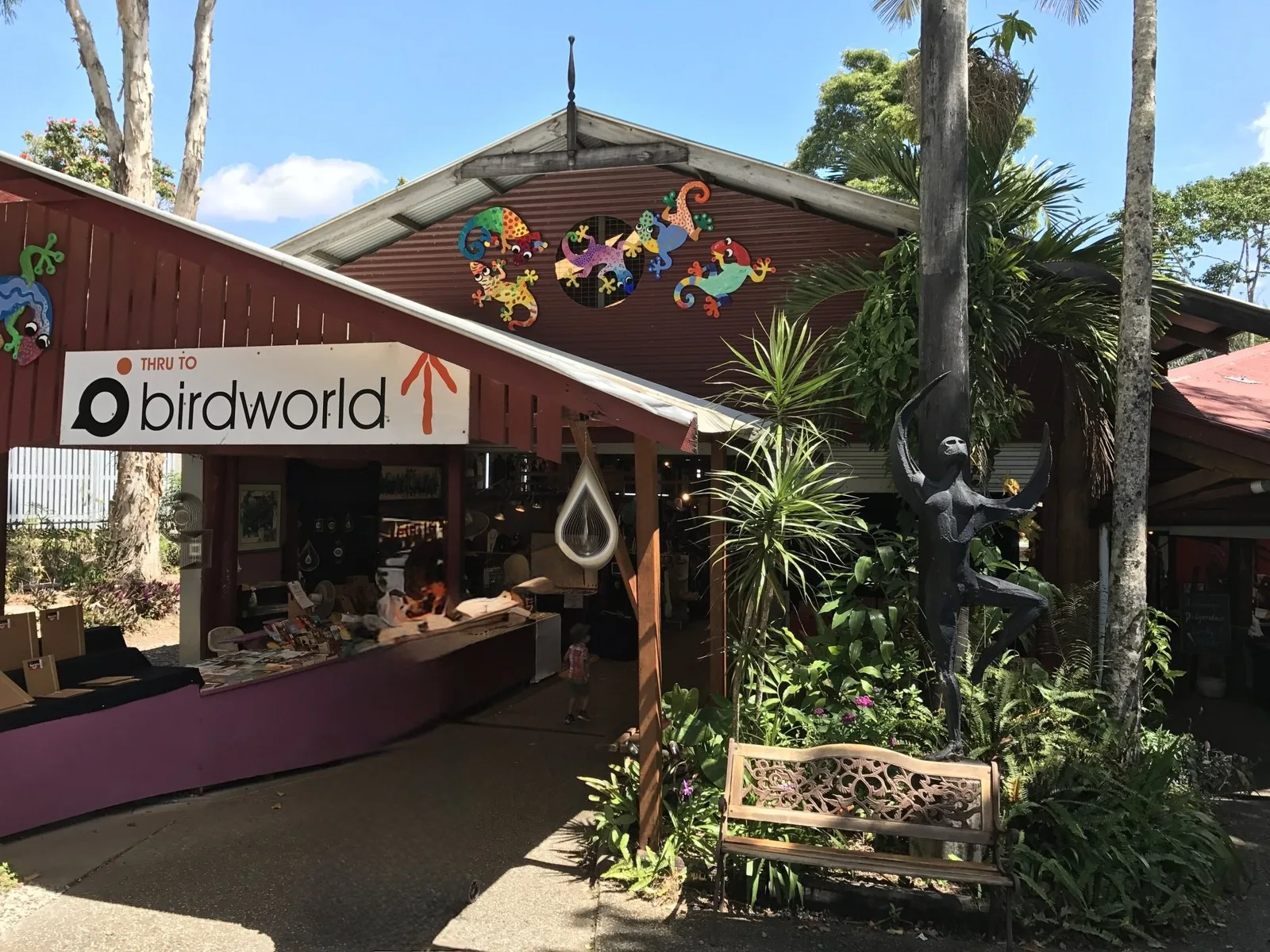 「THRU TO birdworld」の看板とカラフルなヤモリの飾りがある木造の店の入口