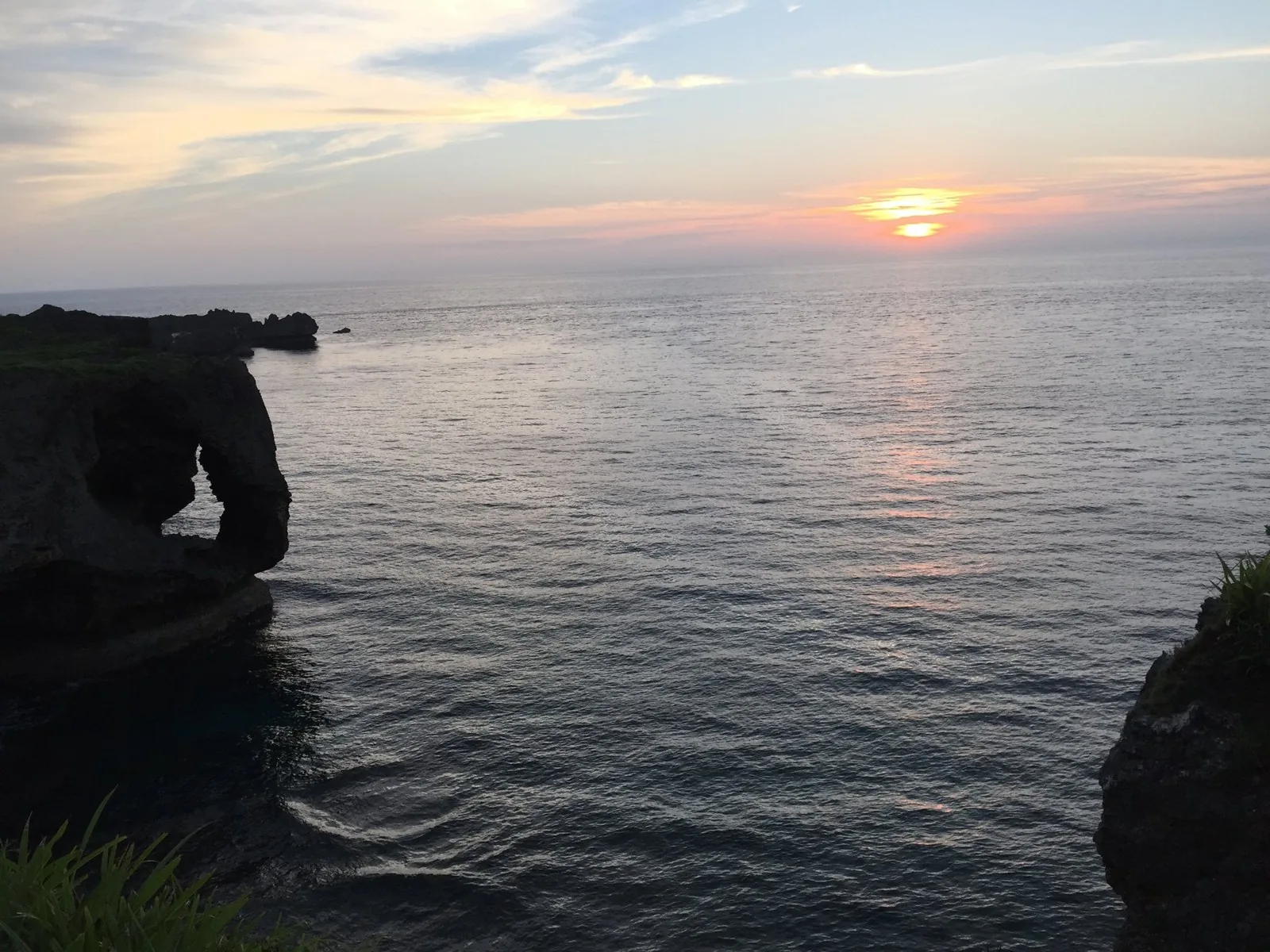 夕日に照らされる万座毛の象の鼻の形の岩