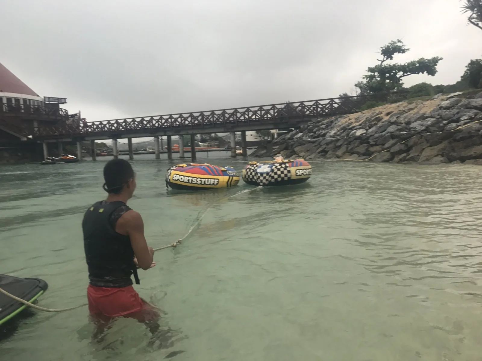 ビーチの浅瀬で、スタッフが水につかりながらチューブを引いているところ