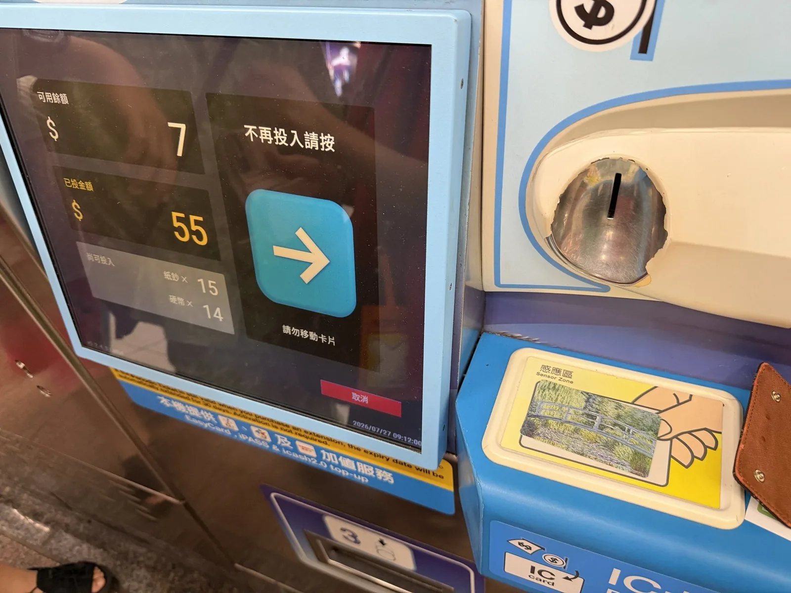 The screen of an IC card top-up machine showing a balance of NT$7 and NT$55 inserted, with a card placed on the reader area